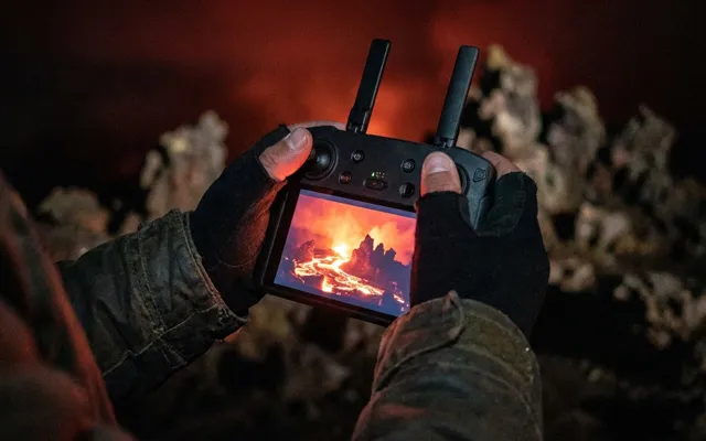 Controller in de hand bij nacht, scherm gloeit rood